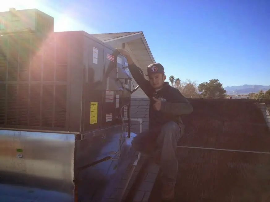 HVAC technician performing HVAC Inspection on a rooftop unit in Harvest